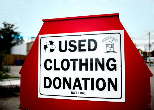 big, red clothing donation bin outside saying "Used Clothing Donation"