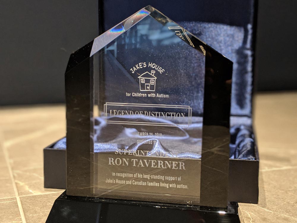 small crystal award in front of case with wording etched on its surface