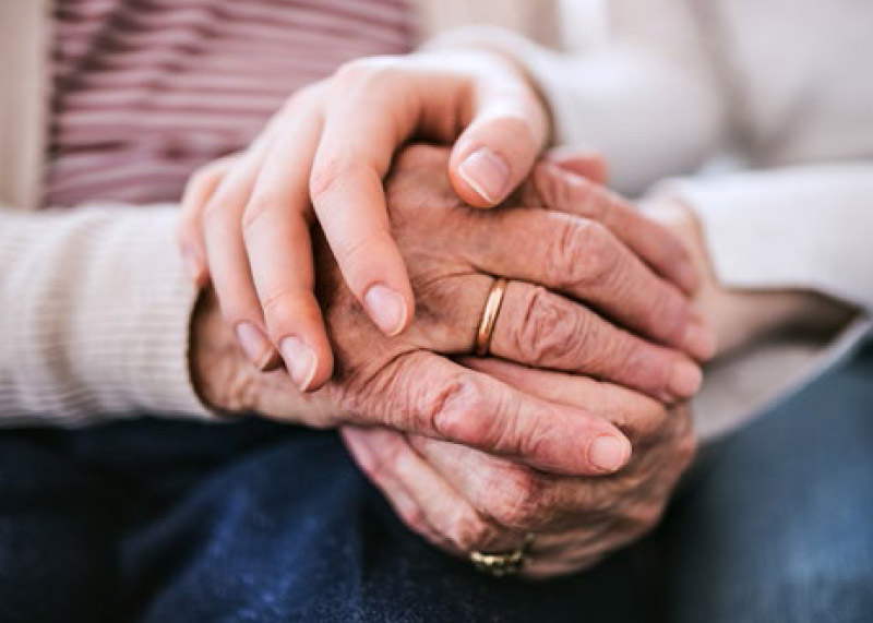 younger hands kindly holding an elder man's hands in support