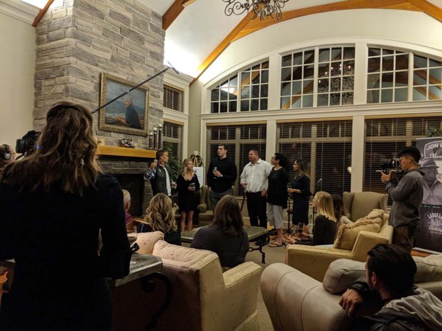 A film crew filming a reception in a grand room with high ceilings, a large stone chimney, and A-frame windows