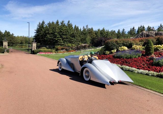 Bad Chad driving away in a silver custom hot rod car on a sunny day