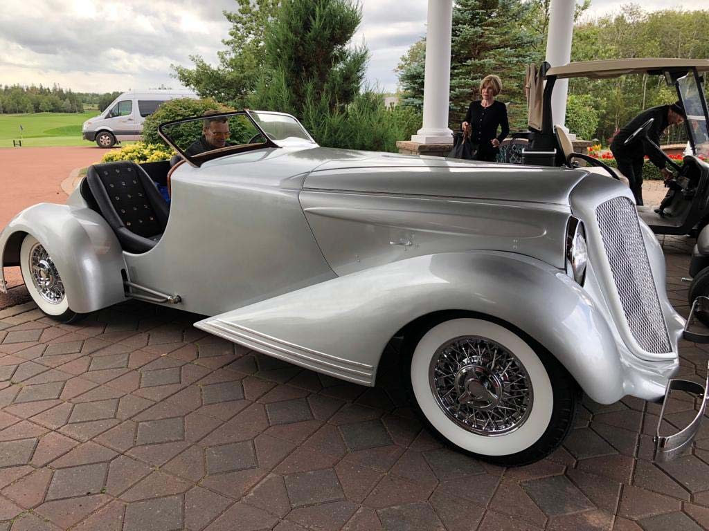 A silver Bad Chad custom hot rod car parked in front of a golf resort entrance