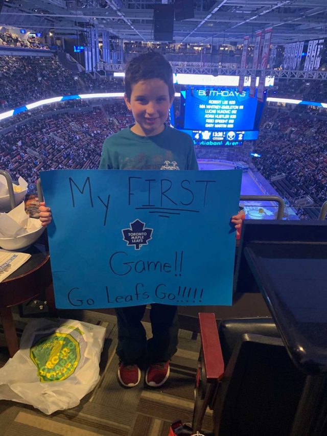 A boy holding up a hand-made cardboard sign at a hockey game