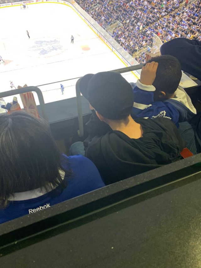 a group of boys looking down at the ice from seats at an NHL hockey game