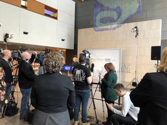 news cameras focused on a woman making an announcement at a press release