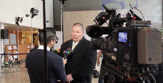 a man shaking hands with a TV news anchor at a press release