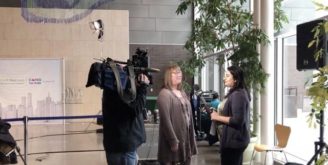 a woman being interviewed by a TV news anchor at a press release