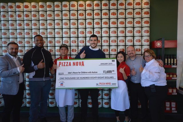 a group of people posing with a giant-sized cheque for a charity donation