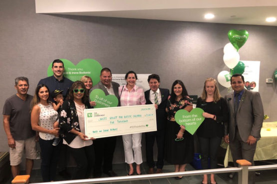 a group of people posing with a giant-sized cheque for a charity donation