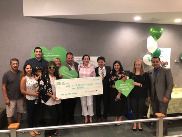 a group of people posing with a giant-sized cheque for a charity donation