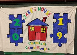 a hand-painted cloth banner for Jake's House Chaminade Camp Olympics 2019