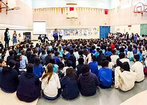 An assembly of grade-school students in a school gymnasium