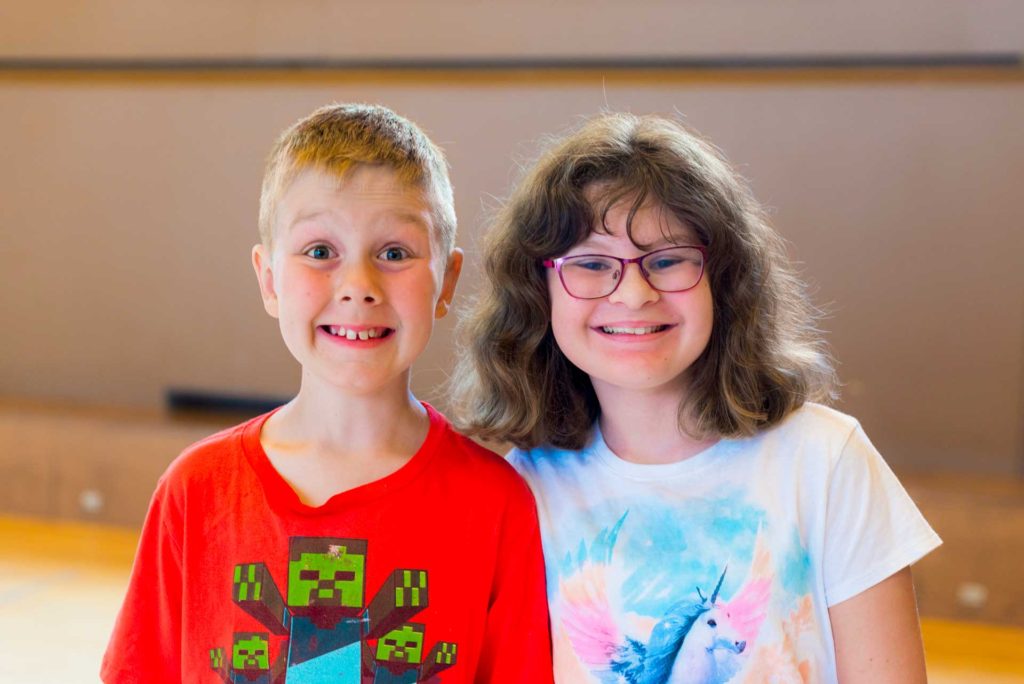 portrait of young boy wearing red shirt and girl wearing white shirt smiling