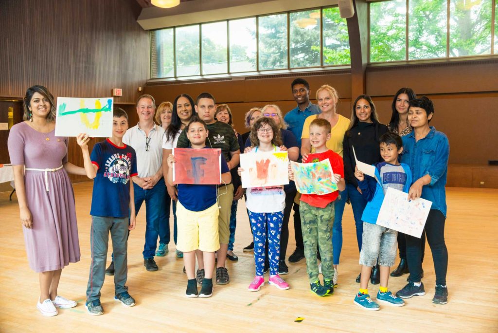 group photo of children holding up artwork with parents in gymnasium